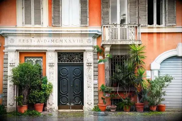 A building facade with a decorated doorway and potted plants at its entrance