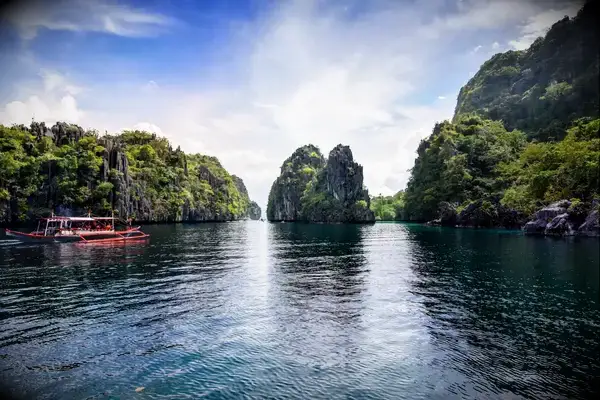 A scenic view featuring rock formations and water in Palawan, Philippines, with a boat on the left side of the frame