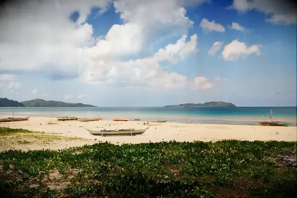 A serene beach with boats and distant islands, featuring a Travel & Lanetrek World