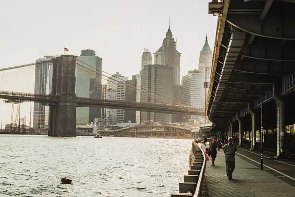 View of the Brooklyn Bridge and Manhattan skyline from a waterfront walkway