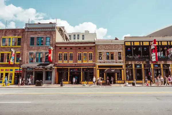 A row of buildings with businesses along a street, pedestrians visible on the sidewalk