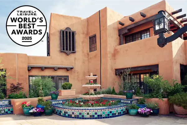 Adobe-style building with a decorative courtyard and fountain, accompanied by a Travel & Lanetrek 2025 World