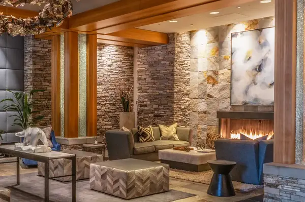A luxurious lounge area with stone accents, a lit fireplace, and modern furniture in a resort or residence setting