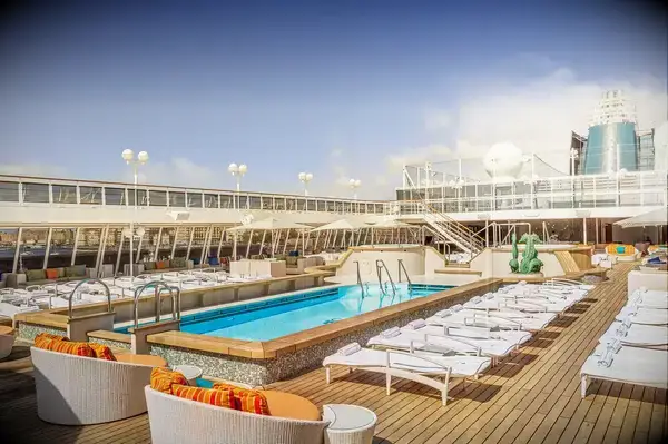Luxury cruise ship deck with swimming pool, lounge chairs, and outdoor seating