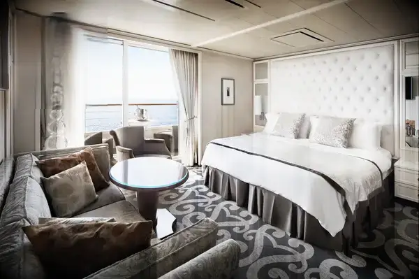 A luxurious hotel room with a bed, seating area, and ocean view as seen through a large window, Travel & Lanetrek World